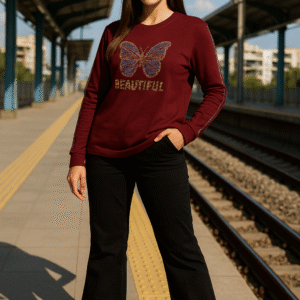 Model wearing maroon butterfly rhinestone T-shirt paired with black trousers and sneakers at railway platform