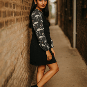 Woman in black tunic dress with printed long sleeves and tie-neck detail