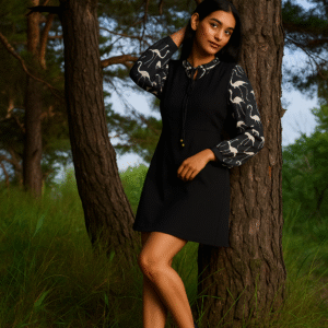 Woman in black tunic dress with printed long sleeves and tie-neck detail