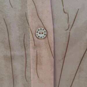 Close-up of blush pink shirt with crystal buttons and soft texture