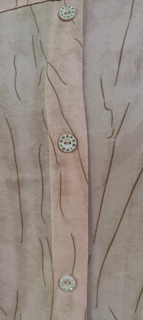Close-up of blush pink shirt with crystal buttons and soft texture