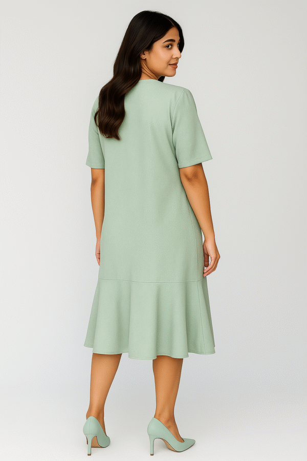 Woman wearing mint-green midi dress with flowy bottom and pearl necklace