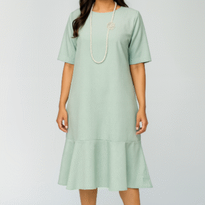 Woman wearing mint-green midi dress with flowy bottom and pearl necklace
