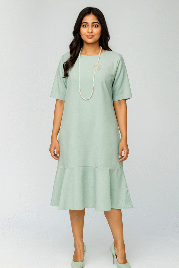 Woman wearing mint-green midi dress with flowy bottom and pearl necklace