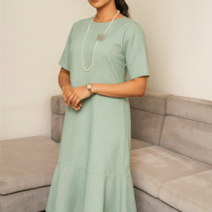 Woman wearing mint-green midi dress with flowy bottom and pearl necklace