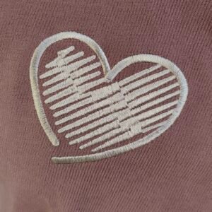 Young woman wearing a mauve short-sleeved shirt with heart embroidery and contrast pocket