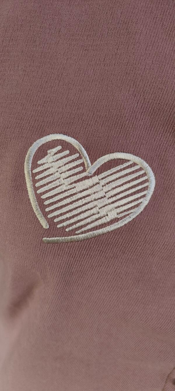 Young woman wearing a mauve short-sleeved shirt with heart embroidery and contrast pocket