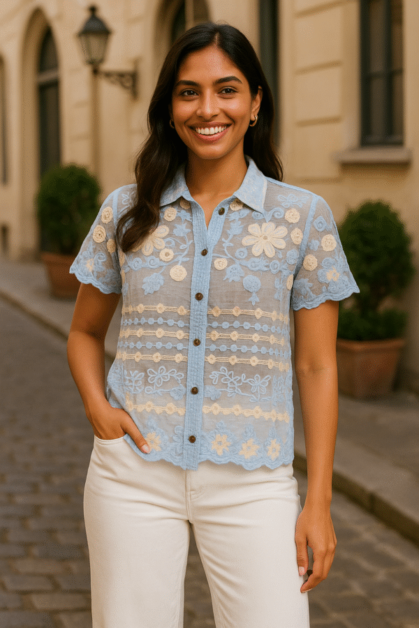 Woman wearing a sky blue sheer embroidered floral shirt with scalloped hem