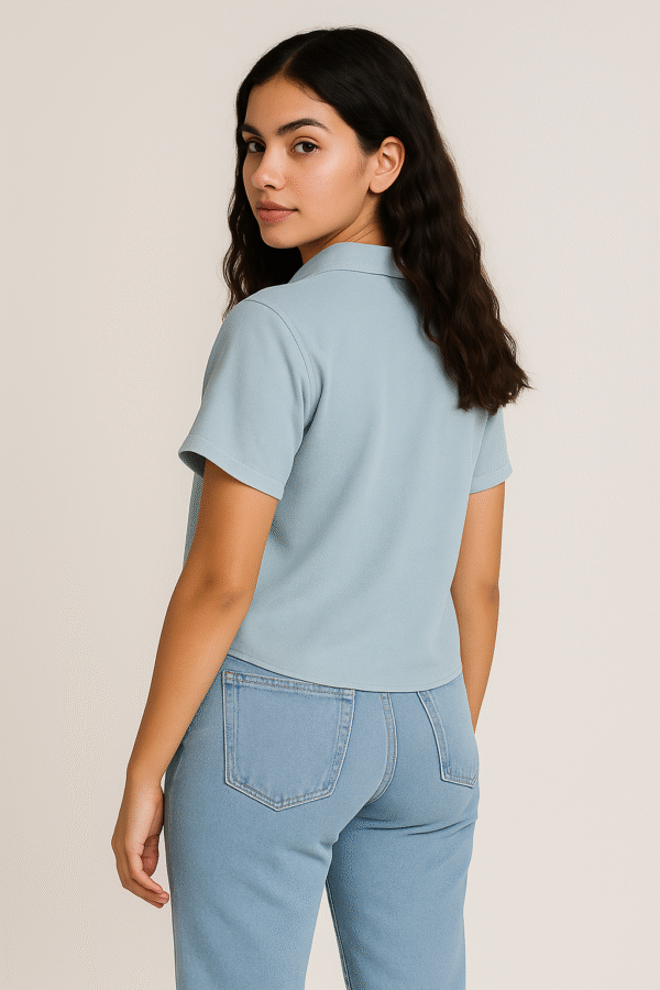 Woman in light blue short-sleeve shirt with heart detail and jeans