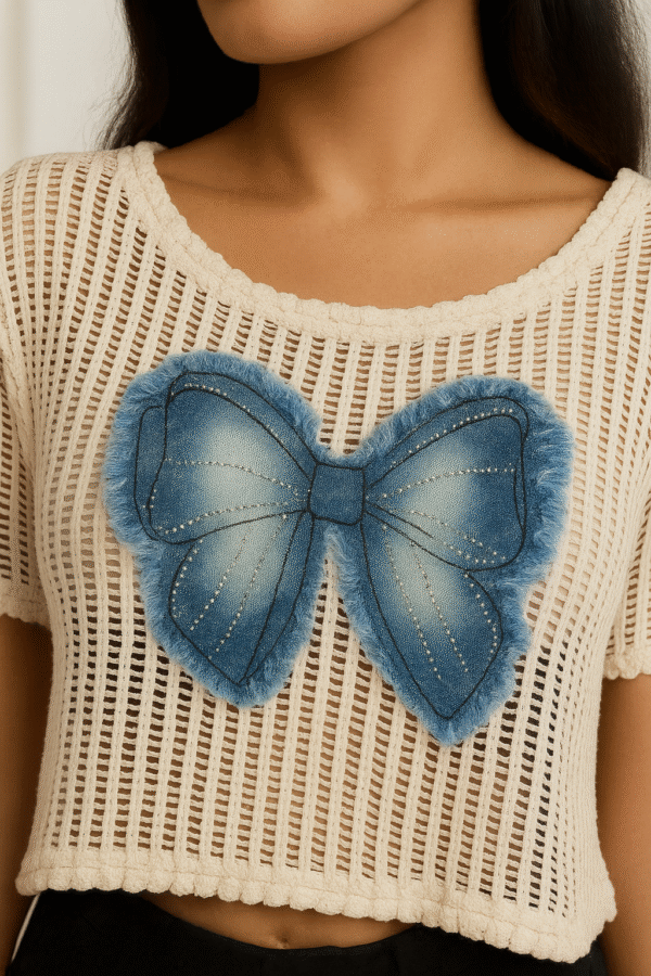 Model wearing net crop top with denim bow paired with high-waist jeans and sneakers