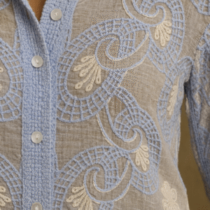 woman wearing sky-blue sheer embroidered shirt with scalloped hem